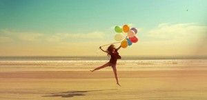 Chica con globos en la playa en actitud positiva